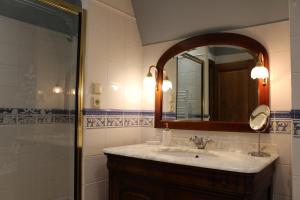 ein Bad mit einem Waschbecken, einem Spiegel und einer Dusche in der Unterkunft La Chaumière Normande 