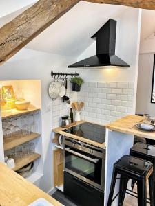 a kitchen with a stove and a black hood at Le repère des sommeliers - Sejour a Auxerre in Auxerre +27 photos