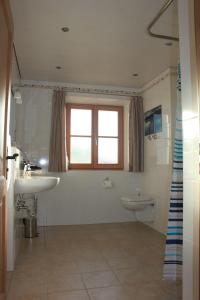 bagno con lavandino, servizi igienici e finestra di Urlaubshof Grimm a Egling