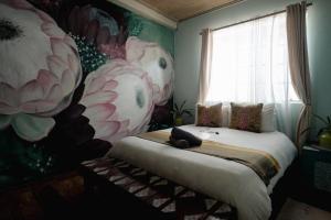a bedroom with a bed with a flower mural on the wall at The Tree Top Village Urban Glamping in St Lucia +39 photos