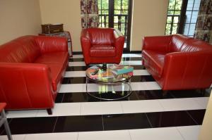 Sala de estar con 2 sillas de cuero rojo y mesa de centro en Guest house Western-city, en Chaudfontaine
