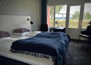 a bedroom with a bed with a blue blanket on it at Sallingsund Færgekro in Nykøbing Mors