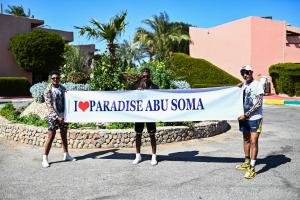 drei Männer mit einem Banner, der das Paradies abu sonka liest in der Unterkunft Eagles Paradise Abu Soma Resort in Hurghada