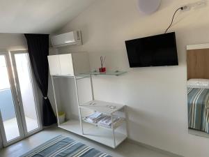 um quarto branco com uma televisão na parede em Hotel Rosa em Rimini