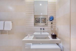 a white bathroom with a sink and a mirror at Spacious Studio Apartment in Hyatt Regency Dubai Creek Heights by the S Holiday Homes in Dubai