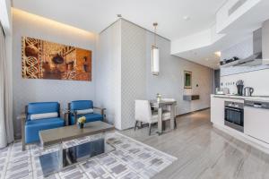 a kitchen and living room with blue chairs and a table at Spacious Studio Apartment in Hyatt Regency Dubai Creek Heights by the S Holiday Homes in Dubai