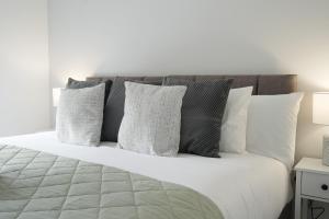 a bed with white and gray pillows on it at Home from Home - Mersey Way, Spacious 3 Bed, Perfect for Workers, Groups & Families, Netflix, FREE Parking & EV Charge Point in Sheffield