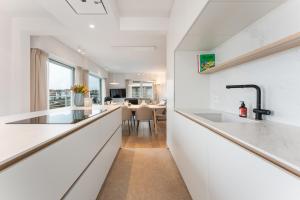 a kitchen with white countertops and a dining room at Ruim en luxueus app met zeezicht én garage - 8p in Knokke-Heist