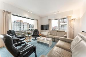 a living room with a couch and chairs and a tv at Ruim en luxueus app met zeezicht én garage - 8p in Knokke-Heist