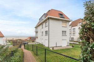 a white building with a red roof at Ruim en luxueus app met zeezicht én garage - 8p in Knokke-Heist