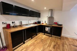 a kitchen with black cabinets and a wooden floor at No.1 - The Marilyn in Banbury