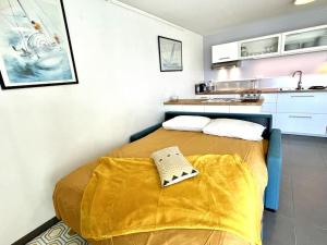 a small bedroom with a bed with a yellow blanket at Très joli T2 en face du plan d'eau d'ETEL in Étel