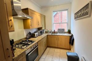a kitchen with wooden cabinets and a stove top oven at NEW! Sleeps 4, Wimborne Centre, Parking & Wi-Fi - The Westborough Willows in Wimborne Minster