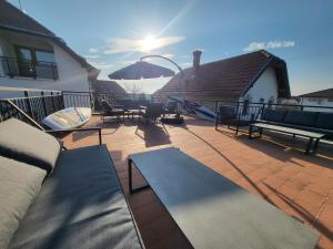 eine Terrasse mit Bänken, einem Tisch und einem Sonnenschirm in der Unterkunft Villa Nova in Hévíz