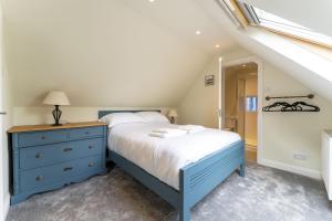 a bedroom with a blue bed and a blue dresser at Garden Cottage in Gargunnock