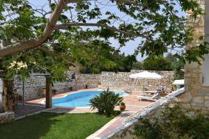 une arrière-cour avec une piscine et un mur en pierre dans l'établissement Anemolia Apartments with pool, à Kampos Paros