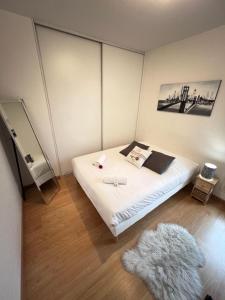 a bedroom with a white bed with a furry rug at Standing, balcon avec vue, clim, tt équipé confort in Échirolles