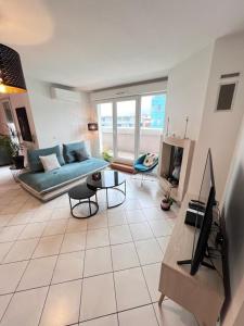 a living room with a couch and a tv at Standing, balcon avec vue, clim, tt équipé confort in Échirolles