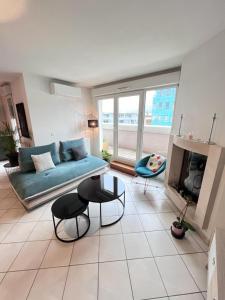 ein Wohnzimmer mit einem blauen Sofa und einem Kamin in der Unterkunft Standing, balcon avec vue, clim, tt équipé confort in Échirolles