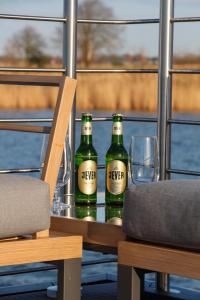 zwei Flaschen Bier auf einem Tisch mit einem Glas in der Unterkunft Hausboot - Nordsonne 11 in Wangerland