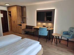 a hotel room with a bed and a desk and a tv at Hotel Waldhorn in Friedrichshafen