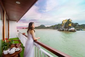 una donna in piedi su un balcone che guarda l'acqua di Le Journey Calypso Pool Cruise Ha Long Bay a Ha Long