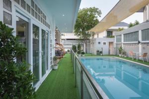 an outdoor swimming pool with green grass next to a house at Large Pool Villa (440 SQM) Near ThongLor BTS. 4 Bedrooms/4.5 Baths. FREE Airport Pickup Service. in Bangkok