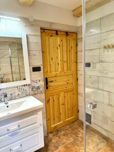 a bathroom with a wooden door and a sink at Chata na Soláni in Vsetín