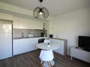 Apartamento Roses, 1 dormitorio, 4 personas - ES-228-110 في روساس: مطبخ مع طاولة بيضاء وتلفزيون