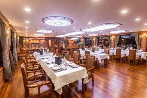 une salle à manger avec des tables et des chaises blanches dans l'établissement Le Journey Calypso Pool Cruise Ha Long Bay, à Hạ Long