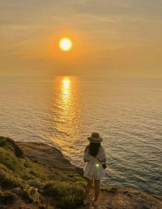 a woman standing on a cliff looking at the sunset at Homestay Lucas's House in Liên Trì (3)
