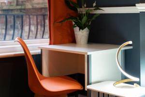 an orange chair sitting next to a desk with a plant at Open Mind Property - 5 Bedroom Lovely Home with Free Parking in Portsmouth