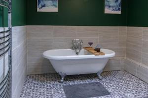 uma banheira na casa de banho com uma parede verde em Open Mind Property - 5 Bedroom Lovely Home with Free Parking em Portsmouth