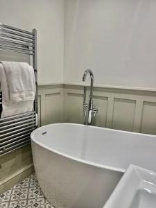 a white bath tub in a bathroom with a sink at No.8 - Garden Square in Banbury