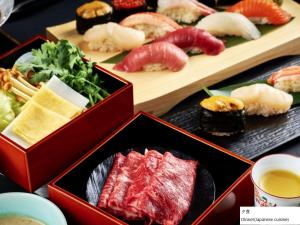 une table avec des assiettes de nourriture et des sushis dans l'établissement La Vista Hakodate Bay Annex, à Hakodate