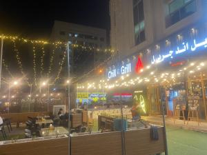 un gruppo di persone seduti ai tavoli di fronte a un edificio con luci di Dream valley hostel a Abu Dhabi