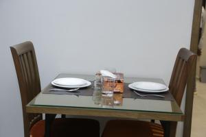 伊斯蘭堡的住宿－Trivelles Executive Suites Islamabad，一张桌子、两把椅子和一张桌子,桌子上放着盘子和眼镜