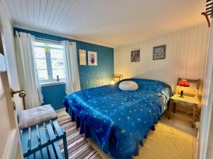 a bedroom with a blue bed and a window at Kleivan Cabin Lofoten in Kvalnes