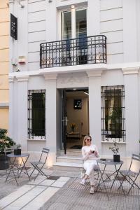 a woman sitting on a chair in front of a building at Sir Athens in Athens