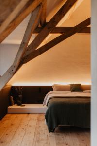 a bedroom with a bed in a loft with wooden floors at Stil 1827 in Sint-Laureins