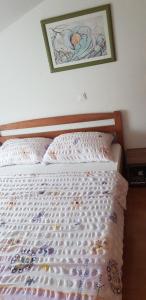a bed in a bedroom with a picture on the wall at Apartments Vučko in Povile
