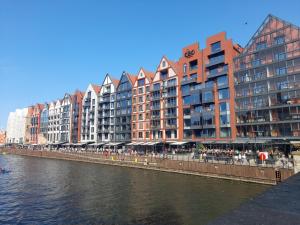 eine Reihe von hohen Gebäuden neben einem Fluss mit Gebäuden in der Unterkunft Apartment with an Amazing View in Danzig