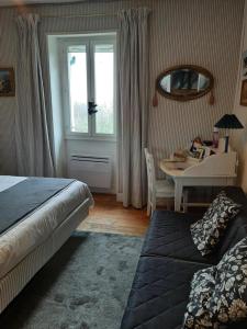 Schlafzimmer mit einem Bett, einem Tisch und einem Fenster in der Unterkunft La Pie qui Chante in Saint-Lamain