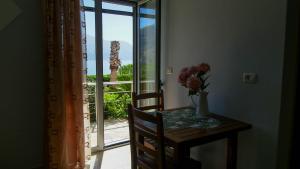 une table avec un vase de fleurs sur une table avec une fenêtre dans l'établissement Guest House Suga 1, à Qeparo