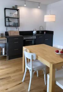 cocina con mesa de madera y sillas blancas en Haus Olga, en Hörbranz
