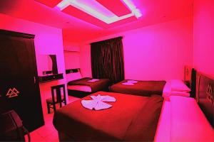 a room with two beds with pink lights in it at MAGIC Pyramids Hotel in Cairo