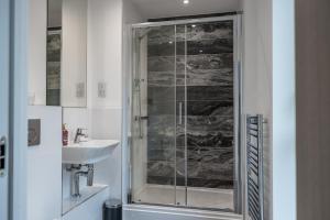 a bathroom with a glass shower and a sink at Penthouse-Central-Free parking in Buckinghamshire