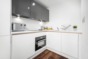 cocina blanca con armarios blancos y microondas en Luxury Birmingham City Centre Apartment - Top Rated - 318H, en Birmingham