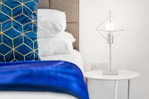 1 dormitorio con cama azul y mesa con lámpara en Luxury Birmingham City Centre Apartment - Top Rated - 318H, en Birmingham