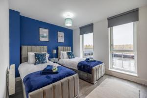 two beds in a room with blue walls and windows at Penthouse-Central-Free parking in Buckinghamshire